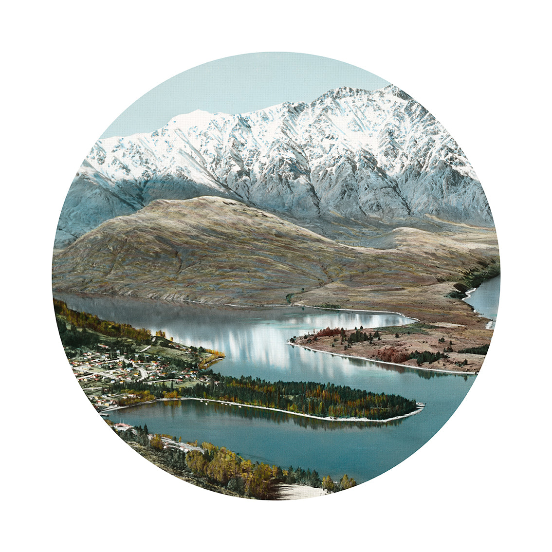 Queenstown Art Spot: A circular image of a lake bordered by a small town, forests, hills, and snowy mountains beneath a clear sky—offered as repositionable wall art for easy decorating.