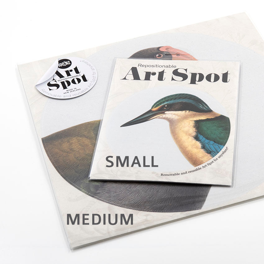 Two sizes of Raw Kawakawa Art Spot packages, each with a bird illustration, are shown: the smaller labeled SMALL sits atop the larger MEDIUM. Both contain repositionable art decals with a matte fabric finish.