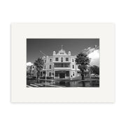 Black and white photo titled Devonport Esplanade - RP023 shows a historic three-story building with columns and a flag, on a palm-lined street in New Zealand—ideal for photographic prints on archival quality paper.