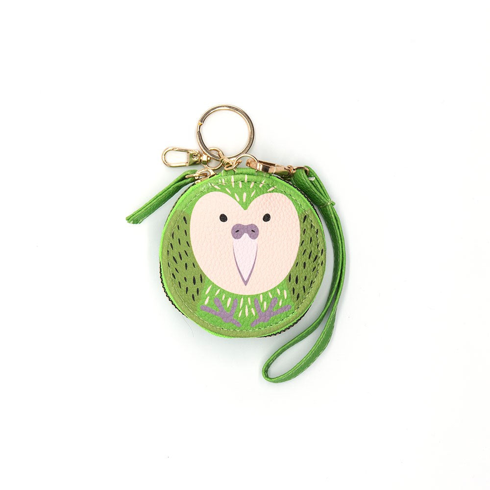 The Kakapo Cutie Coin Purse is a round green purse shaped like a bird with a white heart-shaped face, black dot eyes, and pink beak. It features a green wrist strap, key ring, and gold-colored clip—ideal for fashion fans and bird lovers.