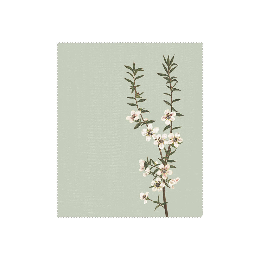 One of the Set of 3 Vintage Botanical Collection Lens Cloths features a thin tree branch with green leaves and white-pink blossoms on a light green background, in a rectangular shape with scalloped edges inspired by New Zealand flora.
