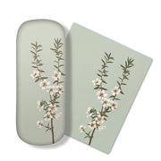 The Vintage Botanical Manuka Glasses Case features a light green case and matching micro-fibre cloth, both adorned with illustrations of flowering branches, perfect for cleaning your glasses or electronics screens.