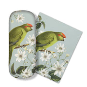 The Birds & Botanicals Kakariki Glasses Case comes with a matching micro-fibre cloth featuring a green parrot with a red forehead on a branch with white flowers—ideal for cleaning glasses or electronic screens.