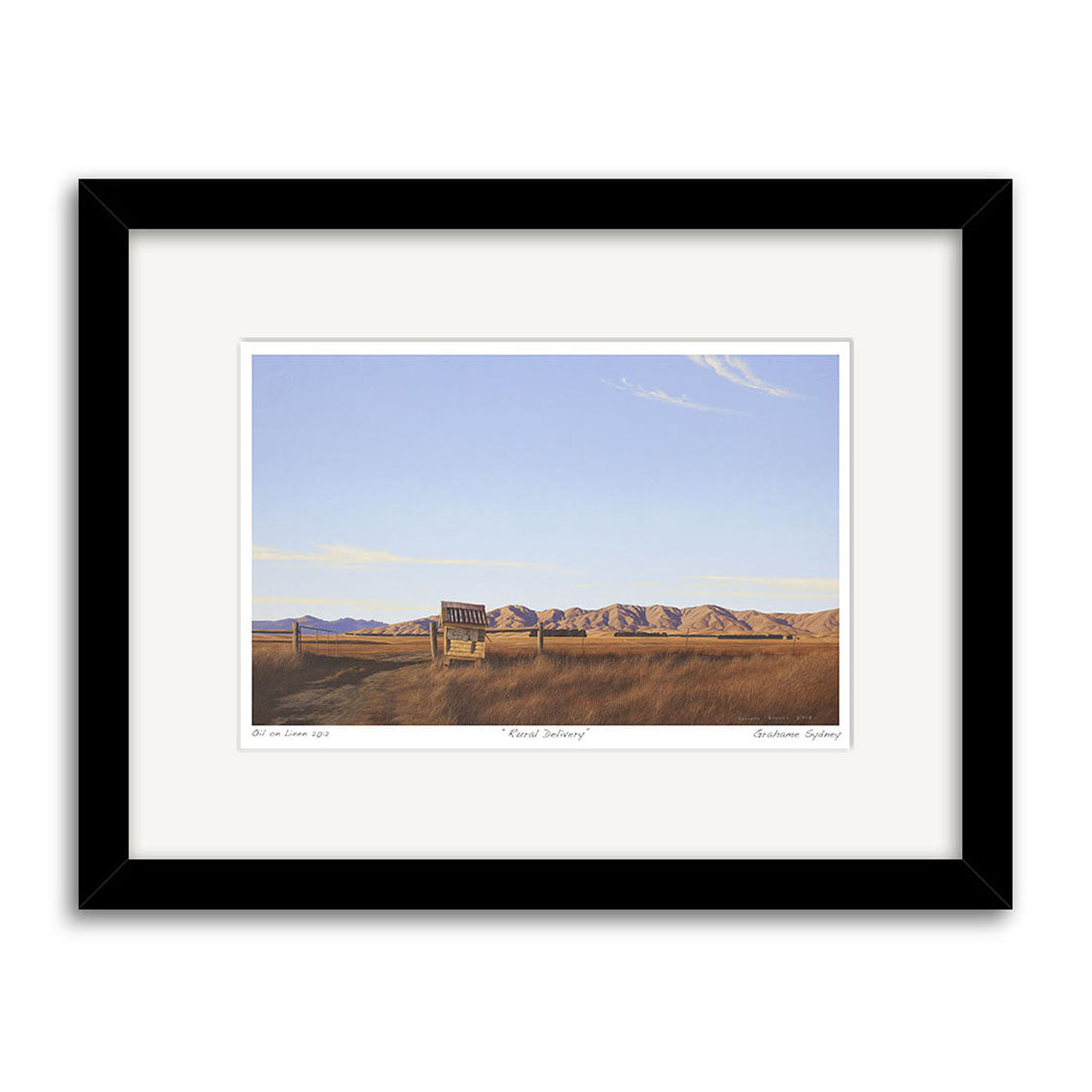 The Grahame Sydney - Rural Delivery Small Art Print features a framed landscape of an empty wooden bench in a grassy field with distant mountains and clear sky, bordered by a white mat and black frame.