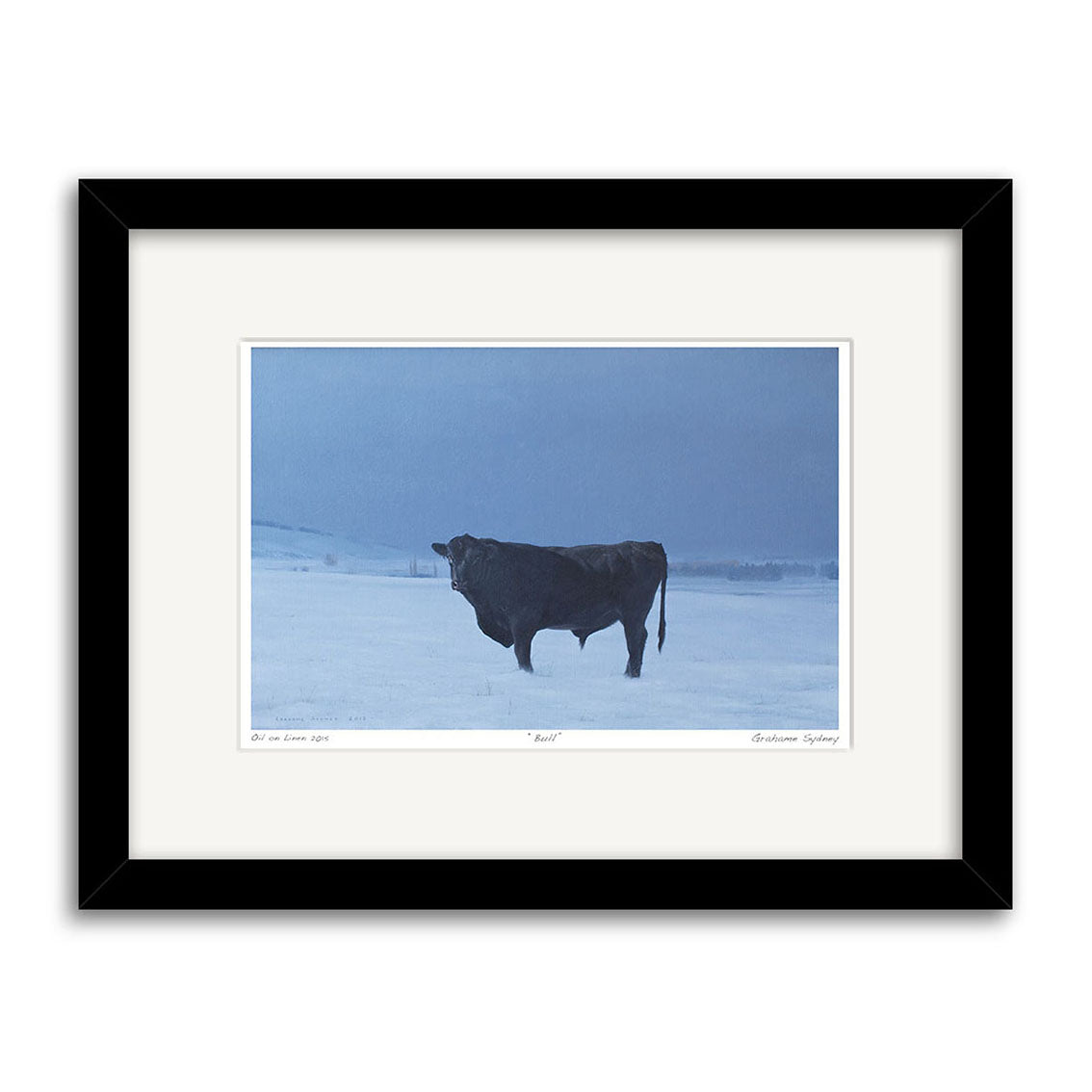 Grahame Sydney - Bull Small Art Print: A framed photo of a black bull in a snowy field under an overcast sky, with distant trees and hills. Features a white mat and black frame, capturing the artists signature New Zealand landscape style.