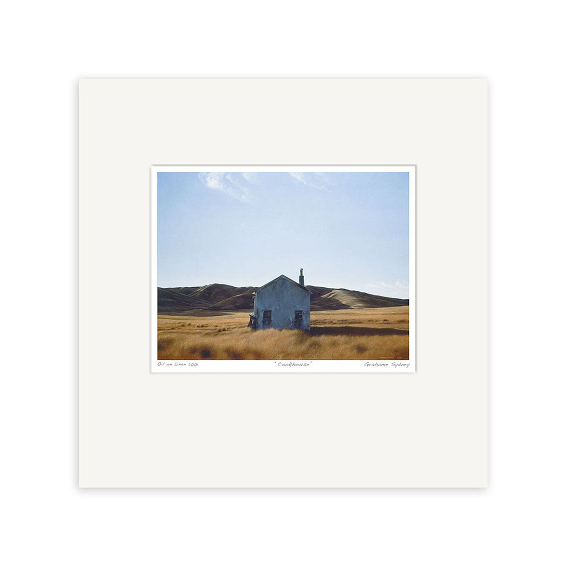 The Grahame Sydney - Cookhouse Small Art Print features a small white house in a dry grassy field with rolling hills and a blue sky, styled after the New Zealand artist. The photo is centered on a wide white mat.