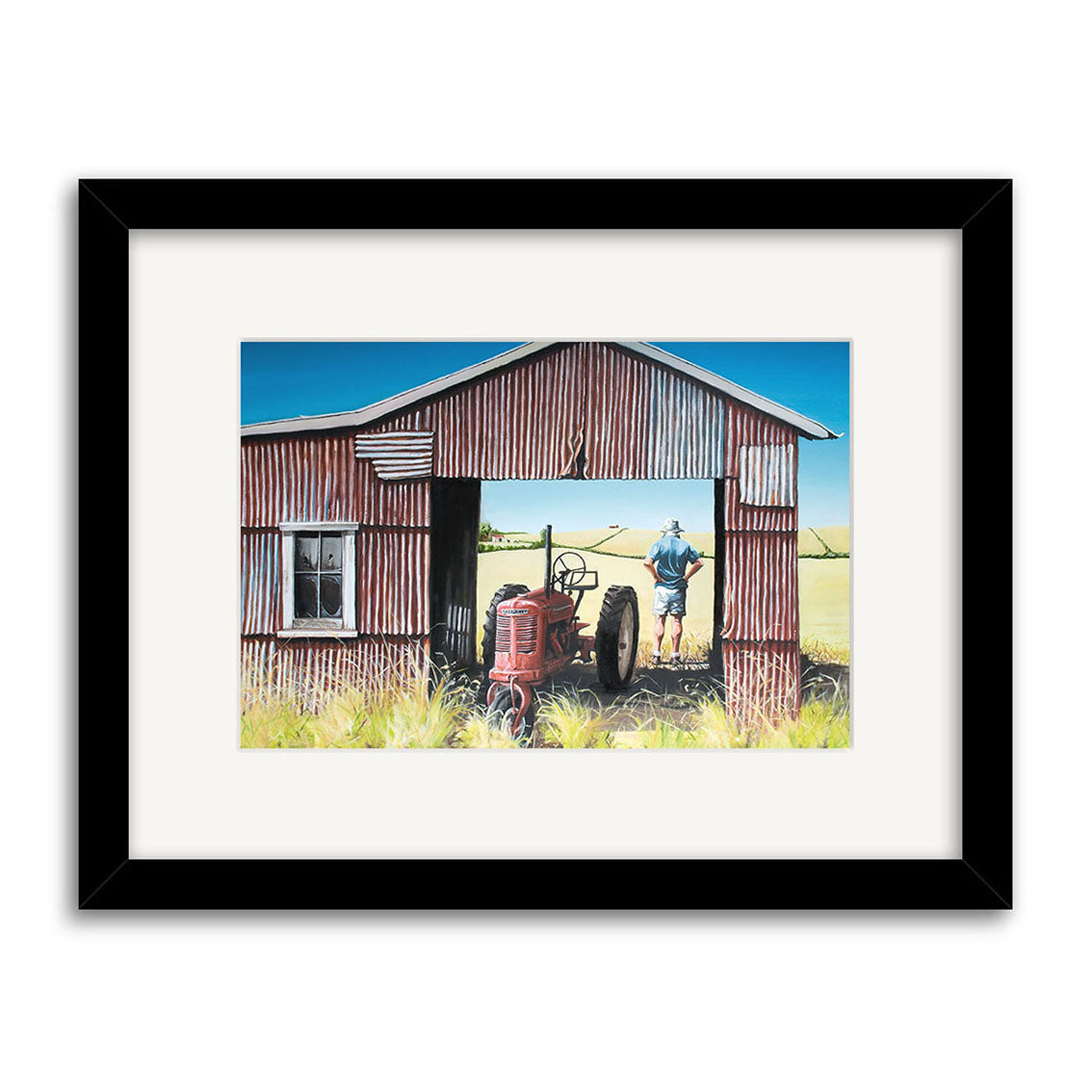 The Graham Young - The Red Barn Small Art Print features a rusted barn sheltering a red tractor, with a figure in the doorway overlooking fields under a blue sky and tall grass. Prints available.