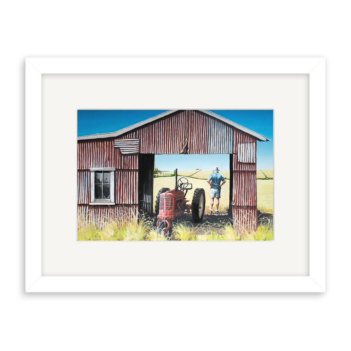 Graham Young - The Red Barn Small Art Print features a red corrugated metal shed with a tractor inside and a person at the door, gazing over a grassy field beneath a clear blue sky. Prints available.
