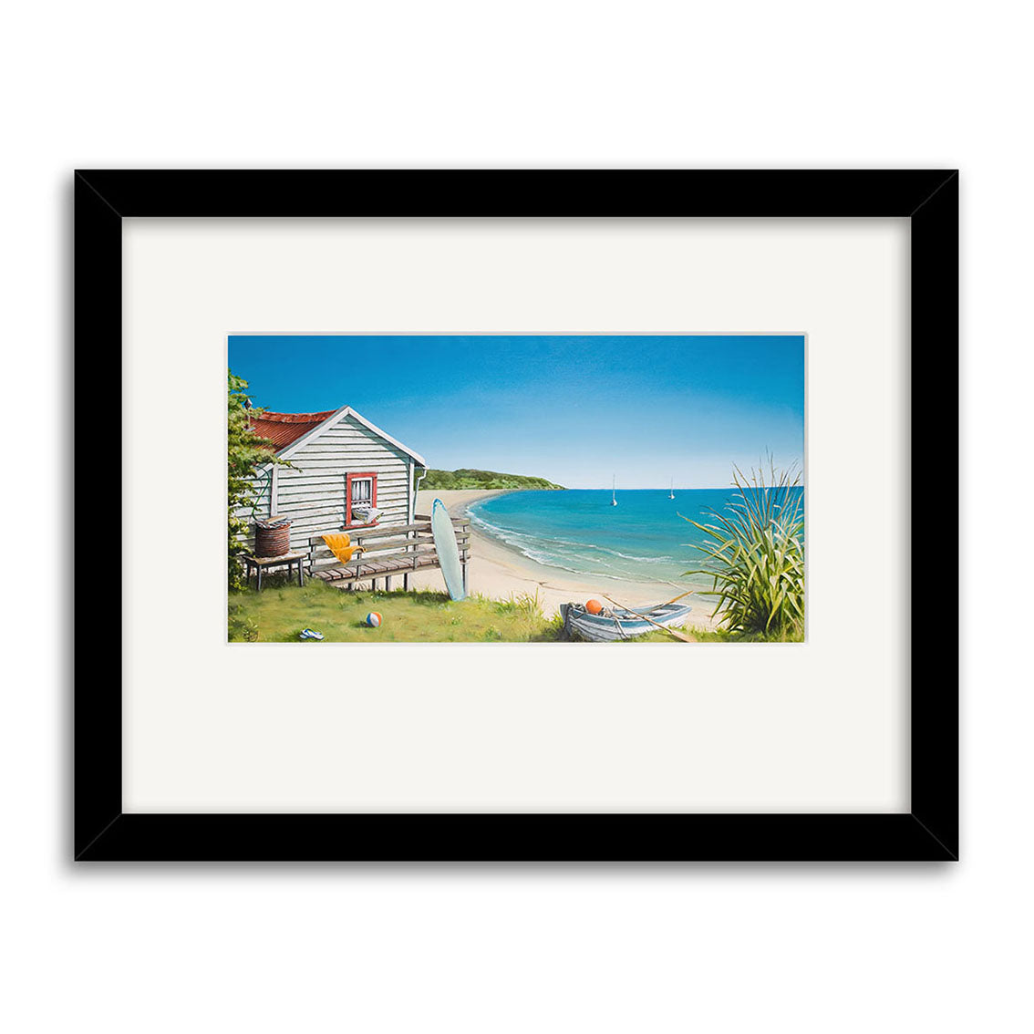 The Graham Young - Bach by the Beach Small Art Print features a white beach house with a red roof, surfboards, a boat, sea grass, and blue sky with sailboats on the ocean in the background.