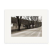 Arrowtown - RP068 features a sepia-toned photographic print of a quiet New Zealand street with leafless trees, small houses, and a distant mountain, showcasing archival quality preservation.