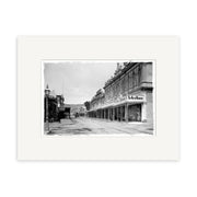 Black and white photo titled Cuba St 1888 - HI002 shows a New Zealand city street lined with multi-story buildings, including visible “Te Aro House” signs, an old-fashioned streetlamp, and is printed on archival quality matte paper.