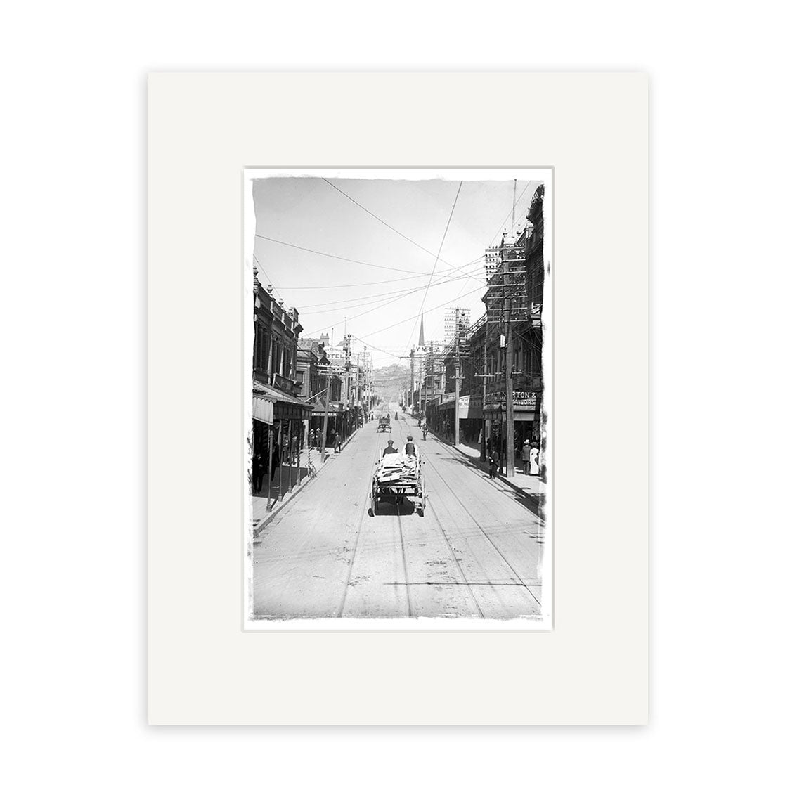 Willis St 1900 - HI013: Black-and-white historic city street photo with trolley tracks, early cars, pedestrians, and buildings (some under construction); hills in the distance. Printed on archival quality matte paper.
