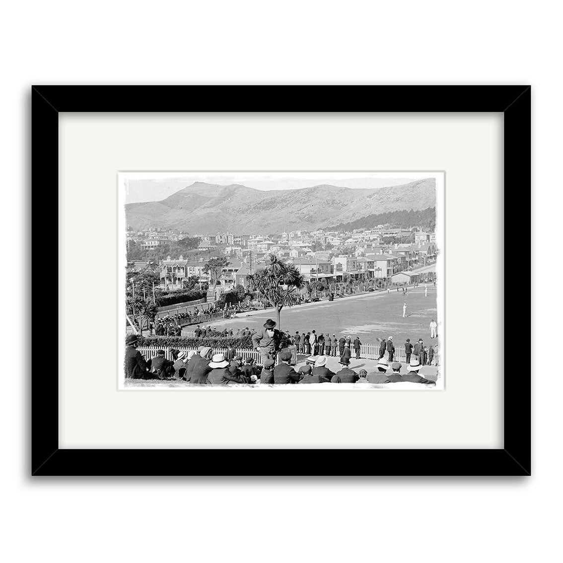 Framed historical photographic print titled Basin Reserve 1900 - HI016, featuring a cricket match with spectators and scenic backdrop, matted on archival quality paper and presented in a simple black frame.