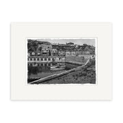Archival quality black and white photographic print, Oriental Bay 1910 - HI020, features a harbor with small boats, waterfront buildings, and hillside homes; centered in a white mat frame. Made in New Zealand.