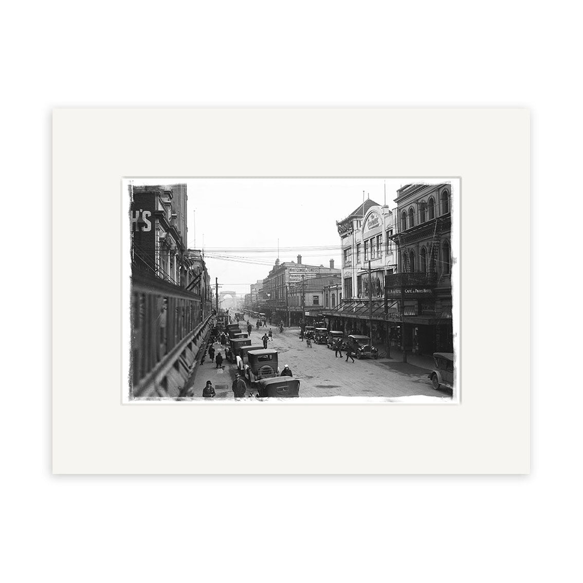 Archival-quality black-and-white photographic print: Cashel St 1930 - HI028 captures a bustling New Zealand city street with cars, horse-drawn wagons, and pedestrians among multi-story buildings from the early 20th century.