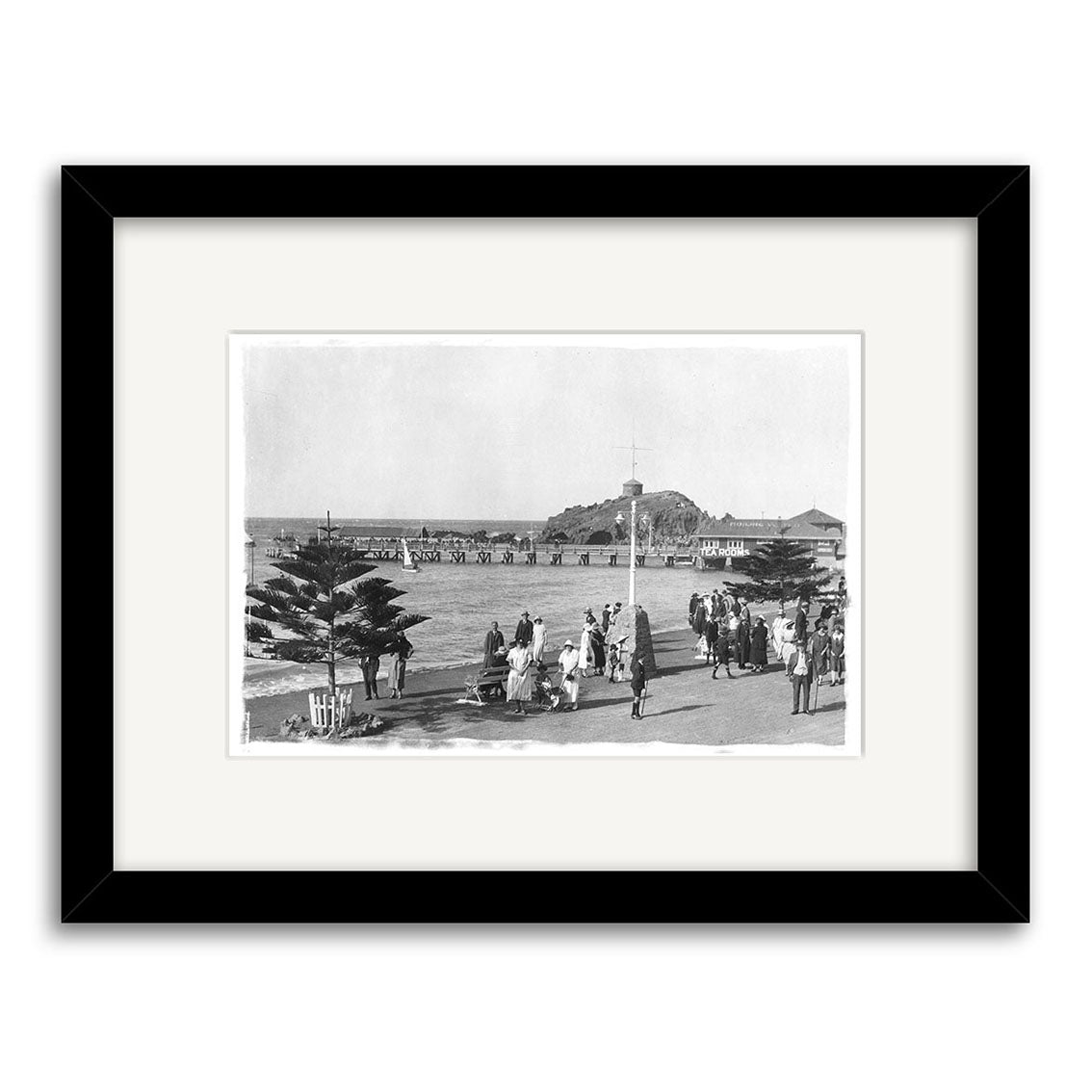 Titled Sumner Christchurch - HI031, this black-and-white framed print shows people in hats and coats on a seaside promenade with trees, a pier, and an island in the background. Printed on archival quality matte paper.