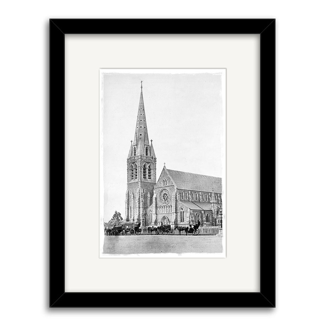 Black and white historical photographic print of Christchurch Cathedral 1880 - HI038, featuring a Gothic-style church with a tall steeple, horse-drawn carriages in front, black frame with white mat, and archival quality for lasting preservation.