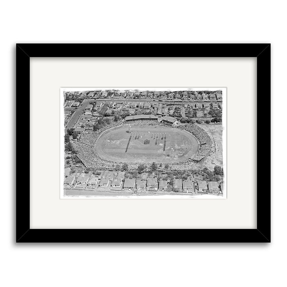 The Eden Park 1950 - HI039 is a black and white aerial photo of a stadium in New Zealand filled with spectators and surrounded by houses, presented as a historical photographic print with archival quality, framed with a white mat and black frame.