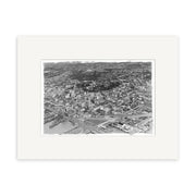 Auckland City 1939 - HI041: An exquisite archival-quality black and white aerial photographic print of Auckland city, featuring buildings, streets, and water in the lower left, elegantly presented with a wide white mat frame.