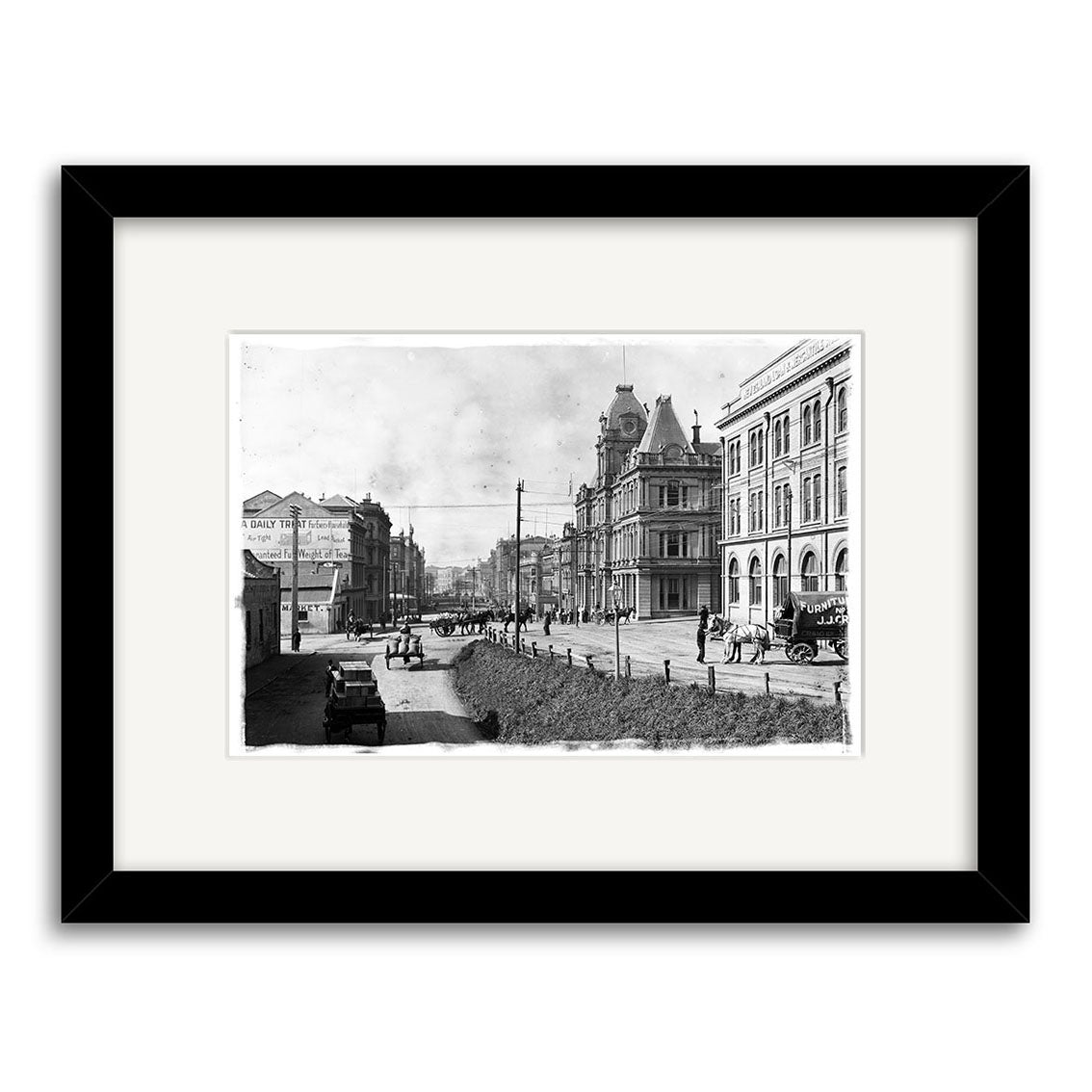 Custom St 1910 - HI044 is a black-and-white photo of a New Zealand city street with horse-drawn carriages, vintage cars, pedestrians, and historic buildings, archivally printed and presented in a white mat with a black frame.