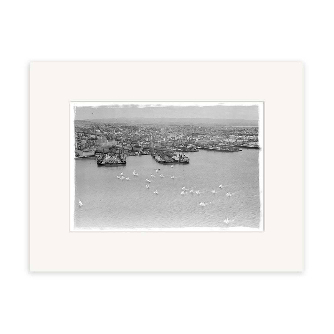 A black-and-white historical print, Anniversary Regatta 1950 - HI047, depicts a New Zealand harbor with buildings, docks, ships, and many small sailboats in the foreground as the city stretches into the background.