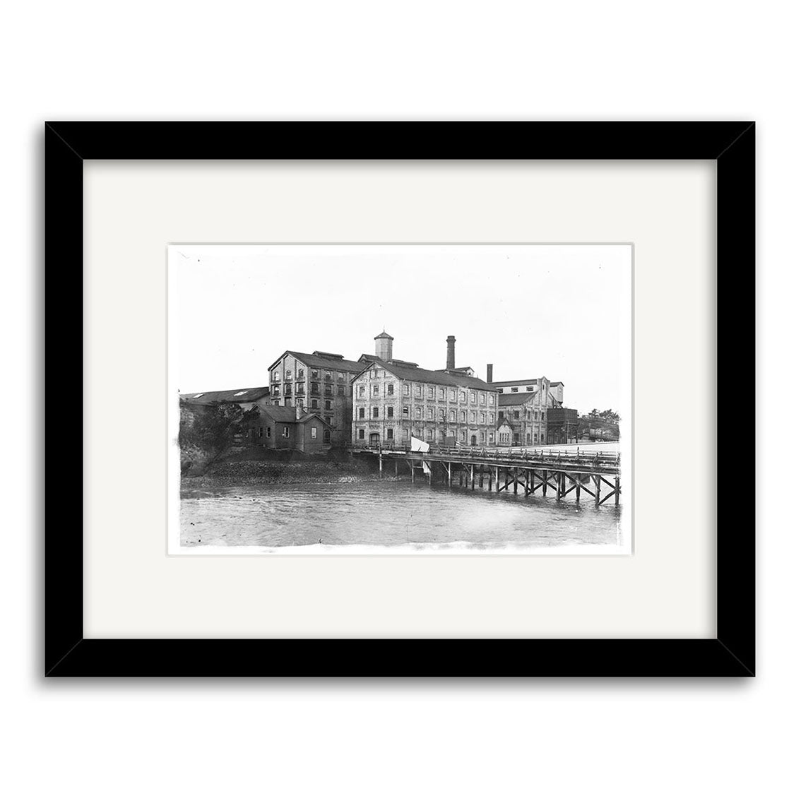 Archival black-and-white historical print, CSW 1915 - HI050: a multi-story industrial building with dock over water, several windows, and a tall chimney in New Zealand. Professionally framed with archival quality materials.