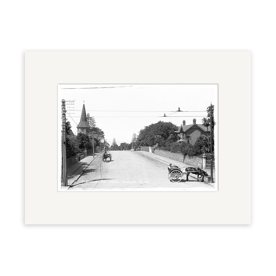 Archival quality black and white historical photographic print: St Stephens Ave Parnell 1910 - HI051 features a quiet New Zealand street with a horse-drawn cart, person nearby, tree-lined road, church steeple on the left, and utility poles.