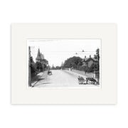 Archival quality black and white historical photographic print: St Stephens Ave Parnell 1910 - HI051 features a quiet New Zealand street with a horse-drawn cart, person nearby, tree-lined road, church steeple on the left, and utility poles.