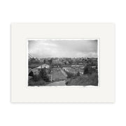 Black and white photo Parnell 1909 - HI052 shows a small town on a hillside under a cloudy sky, bordered by a white mat frame. Printed on archival-quality matte paper for an authentic historical photographic print look.