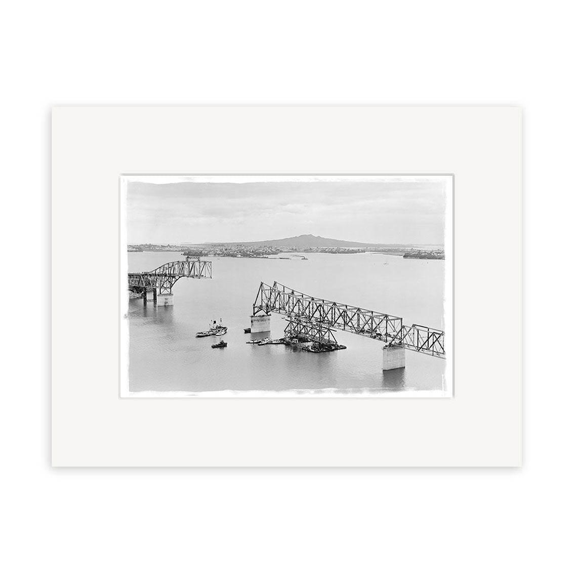 HarbourBridge 1958 - HI054: A black-and-white historical photo print of a partially collapsed steel bridge over water with boats and land, printed on archival matte paper. Made in New Zealand.
