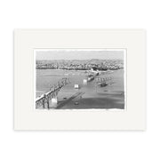 Harbour Bridge 1958 - HI055: Black and white historical photo print of a partially collapsed bridge over water with cityscape in the background. Printed on archival quality matte paper, made in New Zealand.