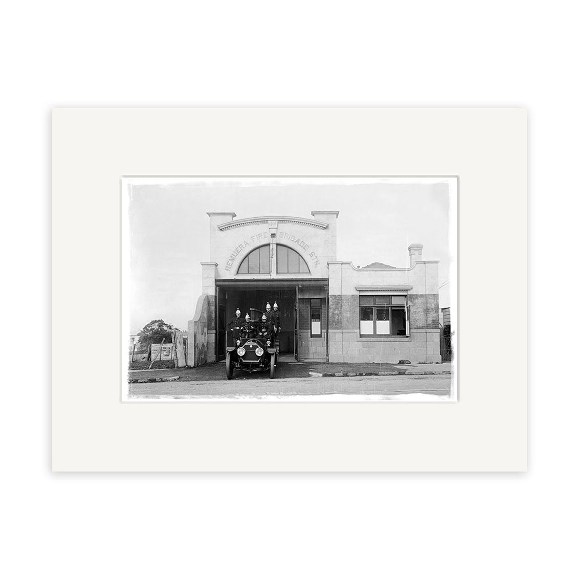 A vintage black-and-white photo titled Remuera Fire Station 1920 - HI056, printed on archival matte paper, shows an old fire truck parked outside a rectangular fire station with a FIRE STATION sign above the entrance.