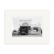 A vintage black-and-white photo titled Remuera Fire Station 1920 - HI056, printed on archival matte paper, shows an old fire truck parked outside a rectangular fire station with a FIRE STATION sign above the entrance.