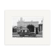 A vintage black-and-white photographic print, Ponsonby Fire Station 1919 - HI057, shows three men in an old-fashioned fire vehicle parked in front of the historic Ponsonby Fire Station with arched windows and ornate details.