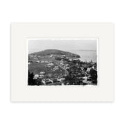 Black and white photo of Devonport 1880 - HI058, showing a coastal New Zealand town with houses, dirt roads, greenery, and a hill by the water. This historical print has a wide white mat border and is made on archival quality paper.