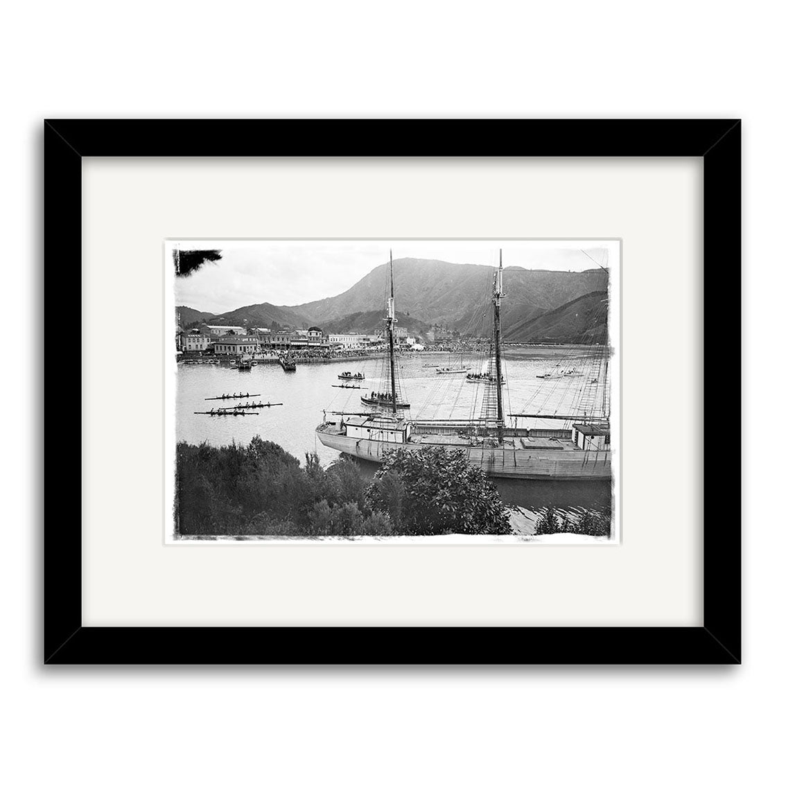 Rowing Regatta 1920 - HI080: Black-and-white historical print of a harbor with a large sailboat, rowboats, and distant hills. Printed on archival matte paper, set in a white mat and black frame.