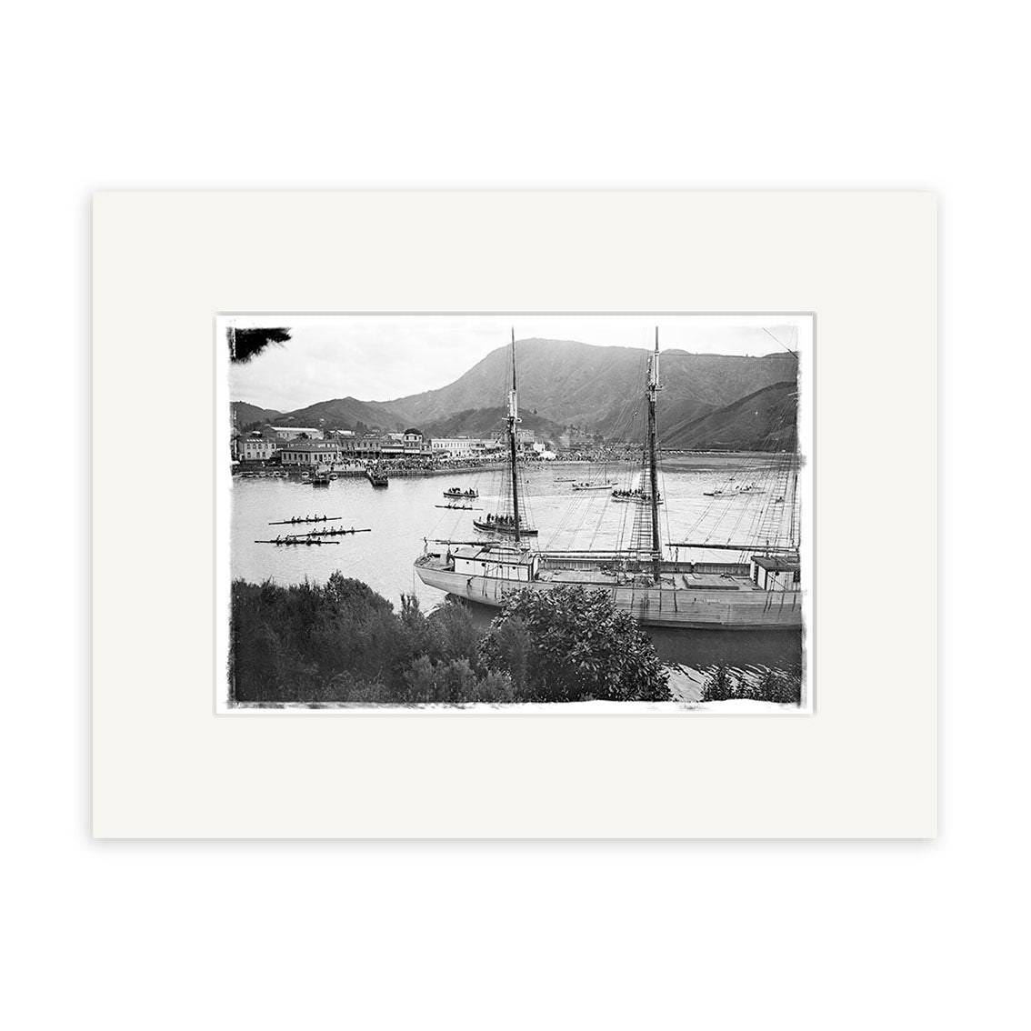 Rowing Regatta 1920 - HI080: Black and white historical photographic print of a harbor with a large ship, rowboats, and distant mountains. Framed with white mat on archival quality matte paper for lasting display.