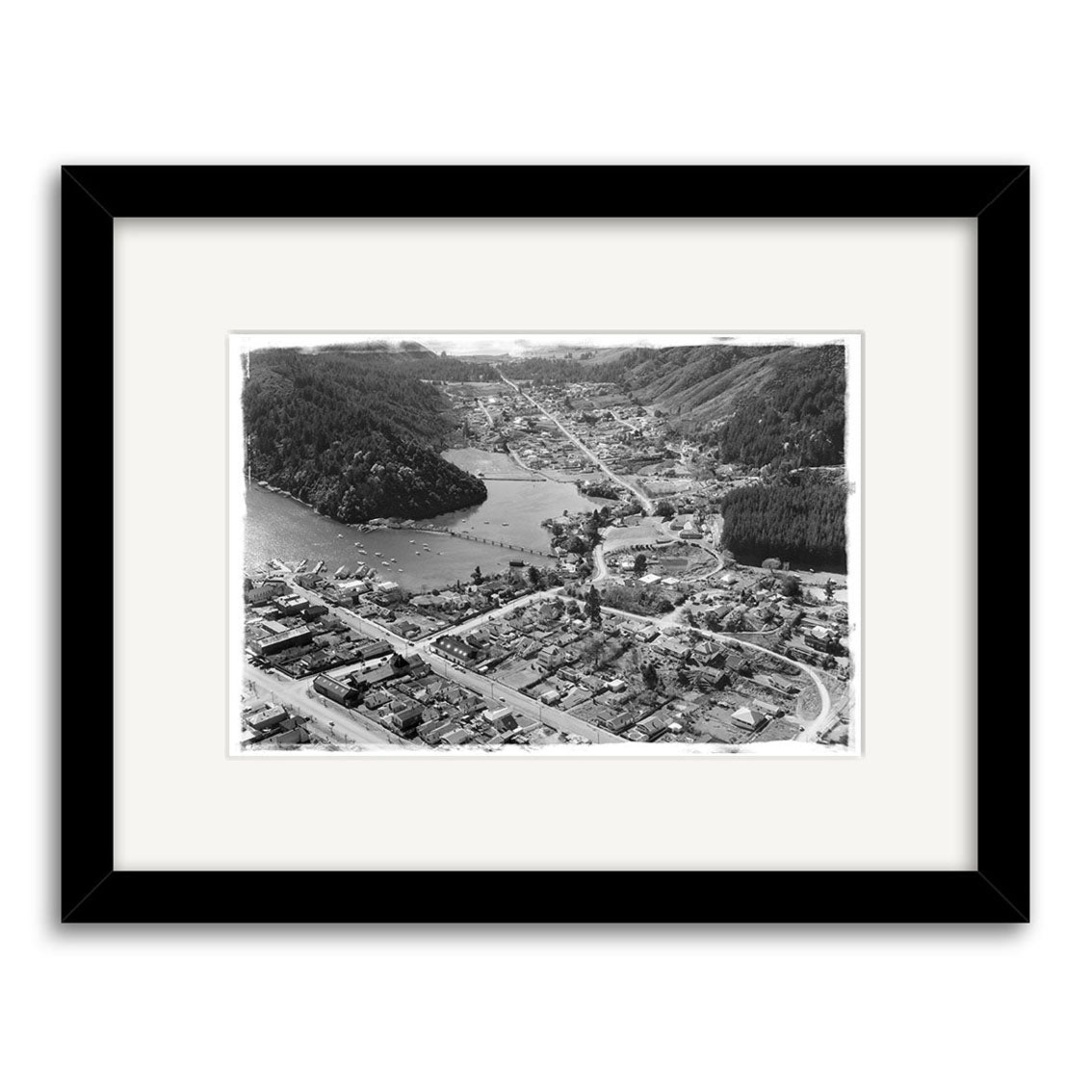 A black and white aerial photo of Picton 1958 - HI082 shows a small town by water with roads, buildings, trees, and hills. This historical print is centered in a white mat and black frame on archival quality matte paper.