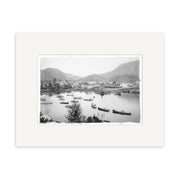 Black and white photograph titled Picton Harbour 1920 - HI085 shows small boats, shoreline buildings, trees, and distant mountains. This historical print is matted with a white border on archival-quality matte paper.
