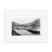 Archival-quality black and white photographic print, Picton Township 1897 - HI086, depicts a New Zealand coastal town with shoreline buildings, a docked ship, and hills; professionally framed with a white mat.