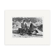 Otago 1900 - HI099 is a historical photographic print showing two people in early 20th-century dress on a handcar along railroad tracks, with hills behind them, made in New Zealand on archival matte paper.