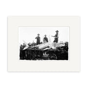 The Port Chalmers 1900 - HI100 print, made in New Zealand on archival matte paper, features a large shark tied to a cart with three men on top, surrounded by a crowd in early 20th-century attire.