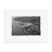 The Queenstown 1957 - HI108 is a black and white aerial photograph, printed on archival quality paper with a white border, showing the town between a lake and forested hills. Made in New Zealand.