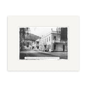 Black-and-white historical print Balarat St 1890 - HI112 shows Ballarat Street, Queenstown, NZ, with people outside Eichardt’s Hotel and buildings, trees, and hills visible in the background. Archival quality image.