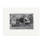 Black and white photo, Golddredge 1930 - HI119, shows people on a wooden ferry crossing a river with rocky cliffs behind. Printed on matte paper, this historical print highlights the ferry’s canopy and central support structure.