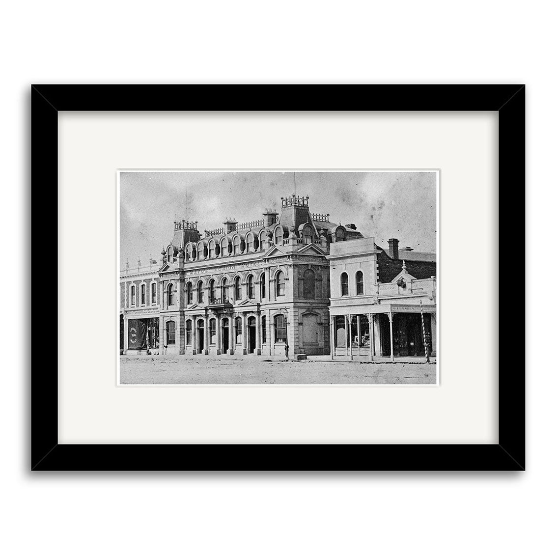Black and white photo of Mayos Albion Hotel 1877 (HI125), a grand Victorian-era two-story building in New Zealand with arched windows and chimneys, framed in black with a white mat. Printed on archival-quality matte paper.