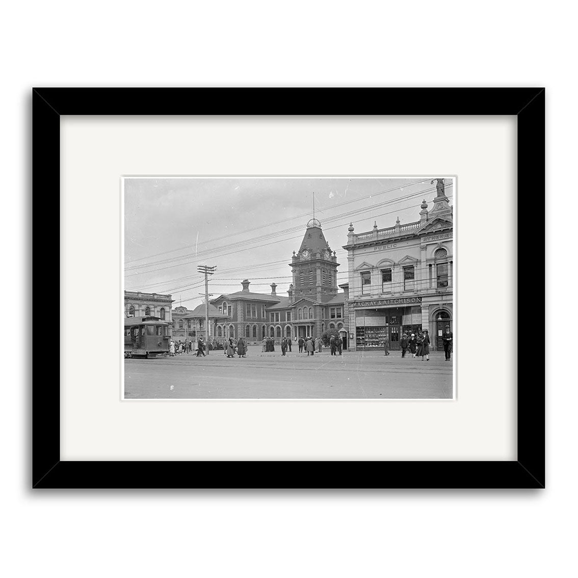 Post Office 1925 - HI126: Black and white photo of a New Zealand town square with people, streetcars, Victorian buildings, clock tower. Framed print with wide white mat and black frame.