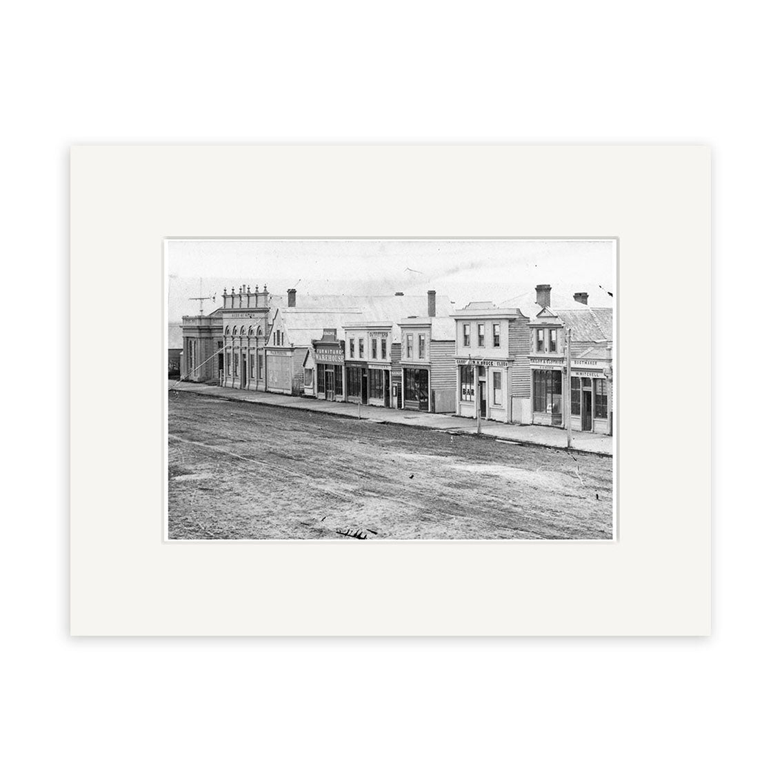Historical black and white photograph Tay St 1864 - HI128 shows a row of commercial buildings on an unpaved street in a historic town. No vehicles or people are present. Printed on archival quality matte paper for lasting beauty.