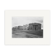 Tay Street 1880 - HI129 is a black and white historical photographic print of a dirt street in New Zealand lined with brick buildings, featuring columns and an arched facade. The archival quality image shows an empty, tranquil scene.