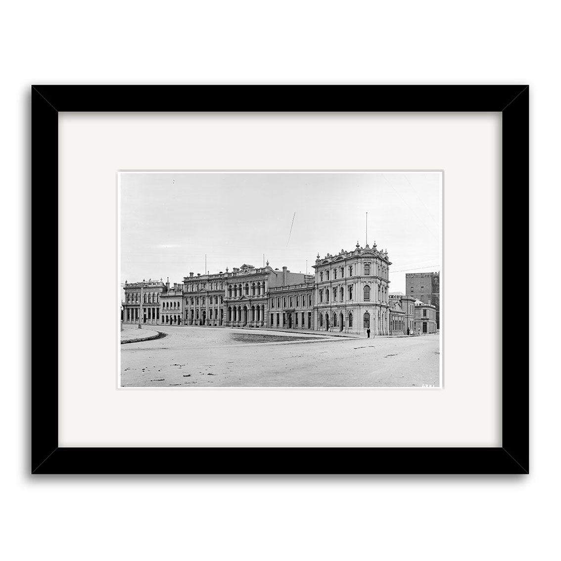 A black and white historical photographic print of The Crescent 1910 - HI130, featuring a large ornate building with classical details, shown in a black frame with white mat and viewed from an open plaza in New Zealand.